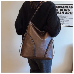 Detail of dark brown vintage PU leather shoulder bag with metallic zipper accents