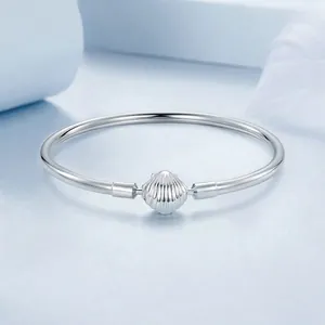 Minimalist s925 sterling silver bangle with a textured shell clasp on blue background