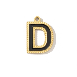 Detail of a vintage gold letter D pendant with black enamel inlay and beaded border
