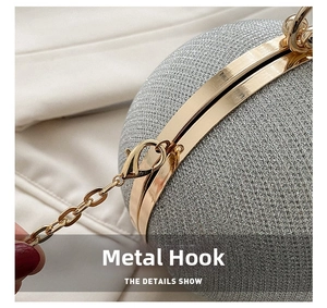 Detailed view of golden metal frame and lobster clasp chain on silver spherical bag