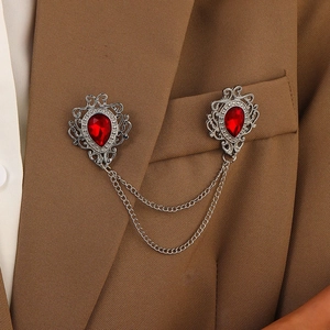 Detail of vintage double brooch with red teardrop stones and silver chains on a suit jacket