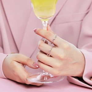 Close-up of S925 silver rings with colorful cubic zirconia worn by a model in pink suit