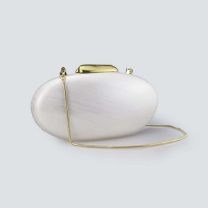 Close-up of white acrylic shell evening bag with pearl finish and gold chain strap