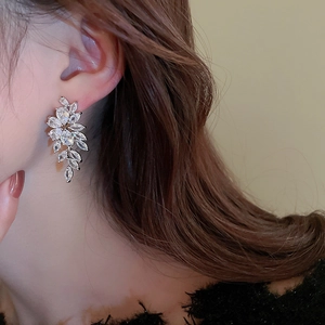 Macro shot of silver leaf tassel earrings with sparkling zircon stones on a model