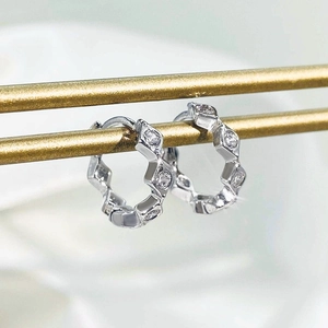 Macro shot of silver-colored wave rhombic earrings with pavé-set white zircon details