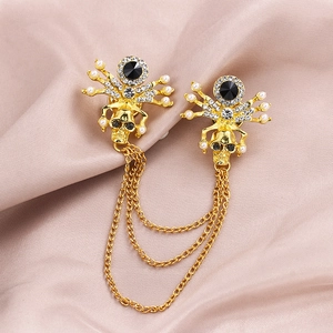 Golden skull and spider brooch pins with pearls and crystals linked by metal chains