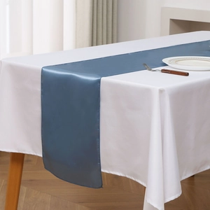 Detail of blue satin table runner showing smooth texture and elegant drape on white cloth