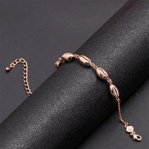 Detail of rose gold shell charm bracelet with lobster clasp on a dark display stand