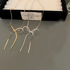 Close-up detail of gold and silver bow snake chain necklaces on a jewelry display