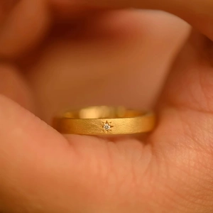 Macro shot of 18k gold plated matte ring featuring a star-shaped inset zircon on finger