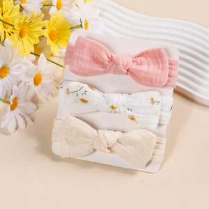 Three-pack of soft cotton muslin baby headbands with bow detailing on a display card