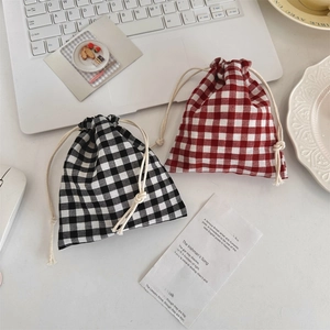 Detail of plaid cotton drawstring storage bags in black and red on a desk