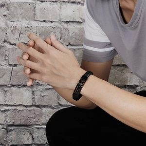 Détail d'un bracelet en cuir tressé noir avec fermoir magnétique noir mat au poignet