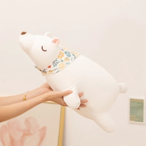 Soft white polar bear plush pillow with floral scarf shown in a cozy home setting