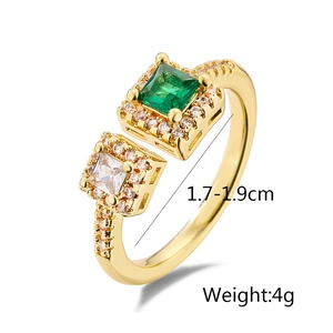 Detail view of gold geometric ring featuring green square gem and cubic zirconia