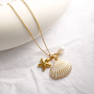 Collier doré avec pendentif étoile de mer, coquillage et perle sur fond minimaliste