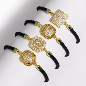Detailed view of four gold geometric charms with micro-pave zircons on black braided ropes