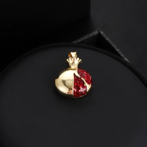 Vue détaillée d'un pendentif grenade doré avec cristaux rouges sur support noir professionnel