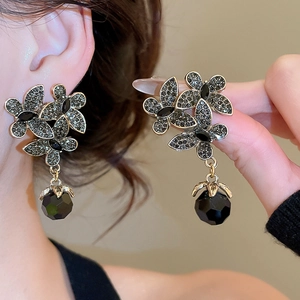 Detailed view of vintage black crystal flower earrings with geometric bead drop on model