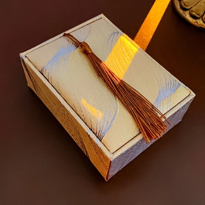 Macro shot of silk jewelry box with wave pattern, brown tassel and golden light beam