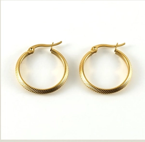 Detail of gold-plated hoop earrings featuring fine diagonal striped texture patterns