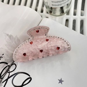 Dettaglio della molletta per capelli in marmo rosa con cuore rosso e strass chiari