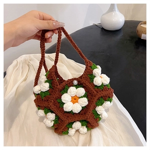 Close-up of handmade crochet bag with brown yarn and white 3D daisy flower patterns