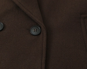 Detailed macro view of dark brown wool coat with textured twill and black buttons