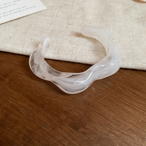 Detailed view of wavy acrylic bangle with translucent white marble texture on linen fabric