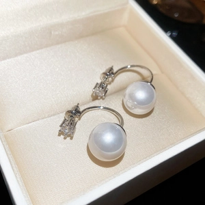 Detailed view of silver zircon stud earrings with large white pearl drop on silk