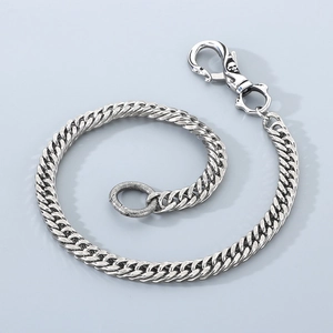 Detail of silver Cuban link pant chain featuring a skull head spring clasp and textured ring