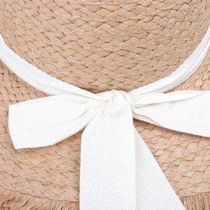 Close-up of natural straw weaving texture with a wide white cotton-linen bow decoration