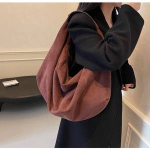 Brown suede tote bag shown on shoulder over a black coat for scale and style