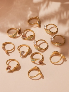 Detail of gold drip oil rings with teardrop zircon on a sunlit beige surface
