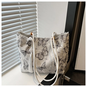 Detail view of large butterfly tote bag with woven rope handles and stylish tassels