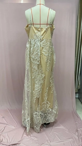 Détail de dentelle blanche sur doublure beige d'une robe longue sans manches à col en V