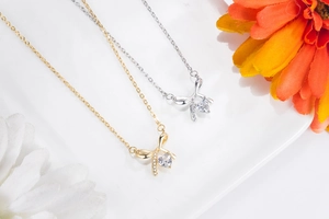 Close-up of bow knot necklaces in gold and silver with heart-shaped zircon pendants
