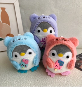 Detail of plush penguin keychains wearing colorful animal hoodies in purple blue and pink