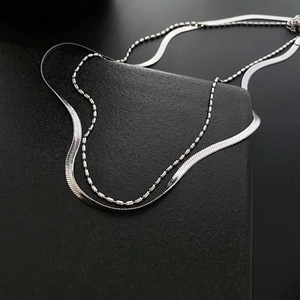 Minimalist silver double-layered necklace featuring snake and bead chains on black background