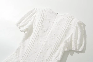 Vue détaillée du dos d'une robe blanche brodée avec fermeture éclair invisible et dentelle