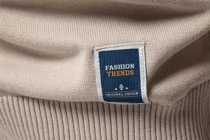 Macro detail of beige knit sweater showing ribbed texture and fashion trend label