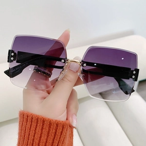 Macro detail of rimless butterfly sunglasses with purple gradient lenses and gold bridge