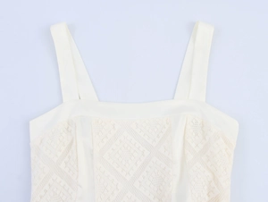 Détail de la robe en dentelle blanche avec décolleté carré et motifs géométriques ajourés