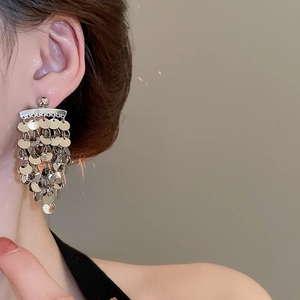 Detailed view of layered silver sequin tassel earrings worn on a model's ear