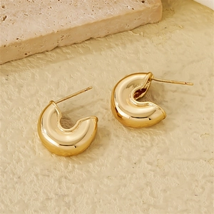 Detail of chunky gold C-shaped hoop earrings with a high-polished mirror finish