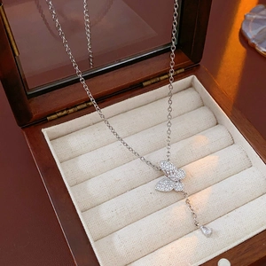 Macro detail of a silver butterfly necklace with zircon stones in a wooden jewelry box