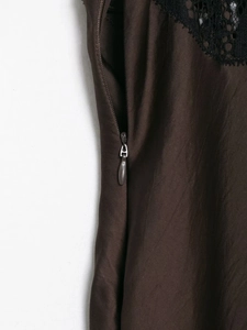 Detail of a dark brown lace dress featuring a precise invisible zipper and fine texture