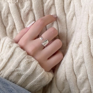 Minimalist adjustable silver ring featuring a small bead and rectangular surface on a model