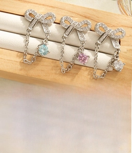 Close-up of silver bow earrings with light blue, pink and clear zircons on wood