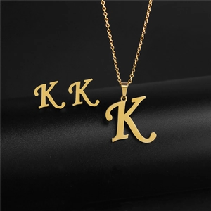 Detail of gold-plated letter K pendant necklace and matching stud earrings set on black stand